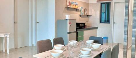 A dining area with a table set for six, chairs, a ceiling fan, and a kitchen in the background.