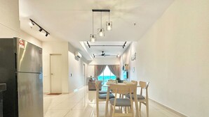 A modern kitchen with a stainless steel refrigerator, a dining area with wooden chairs and a table, and a ceiling fan. - Melaka Ong Kim Wee Residence by Stayrene (Malacca City)