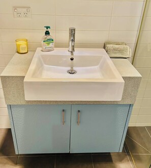 Ein Badezimmer mit Waschbecken, Seifenspender, Kerze und Handtuch.