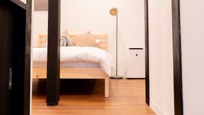 A bedroom with a wooden bed, a bedside table, and a floor lamp. - JP RESERVE Tenshitsukinuke (Kyoto)
