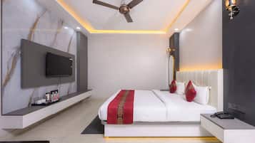 A modern bedroom with a bed, a TV mounted on the wall, a ceiling fan, and a bedside table with a phone.