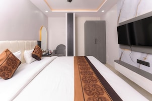 Una habitación de hotel moderna con una cama grande, un televisor de pantalla plana en la pared, un armario y una zona de estar con una silla.