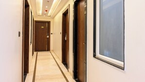 A hotel corridor with doors, a marble floor, and a large window on the right. - Hotel Maharani Palace (varanasi)