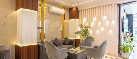 A modern living room with a sofa, two armchairs, a coffee table, and a potted plant.