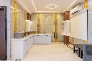 A modern bathroom with a marble floor, a sink with a mirror, and a shower area. - Hotel Maharani Palace (varanasi)