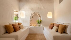 Ein Zimmer mit zwei weißen Sofas, einem gewebten Teppich, einem Steingewölbe und Wandleuchten.