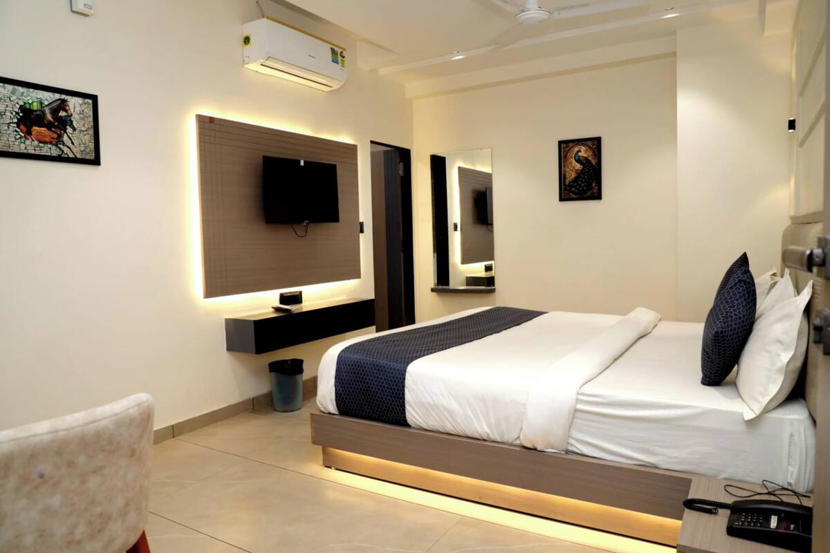 A modern hotel room with a large bed, bedside tables, a TV, and a mirror.
