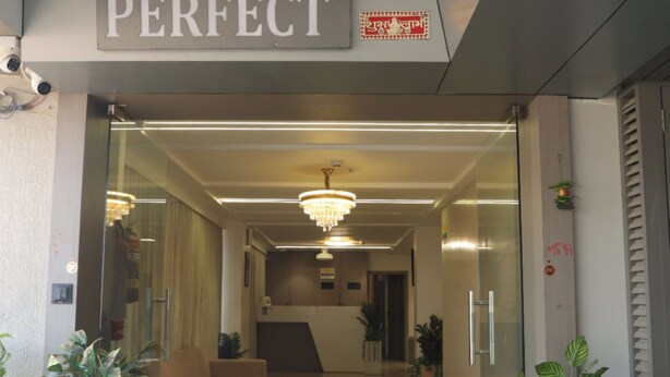 Der Eingang vom Hotel The Perfect mit einem gut sichtbaren Schild, einer Kristallleuchtre und Topfpflanzen.