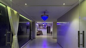 Ein moderner Korridor mit einer Rezeption, einer Chandelüster und einer Glastrennwand links.