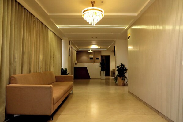 A hotel lobby with a sofa, a chandelier, a reception desk, and potted plants. - HOTEL THE PERFECT (Ahmedabad)