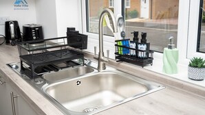 Une cuisine moderne dotée d’un évier en acier inoxydable, d’un égouttoir et d’une fenêtre donnant sur la rue.