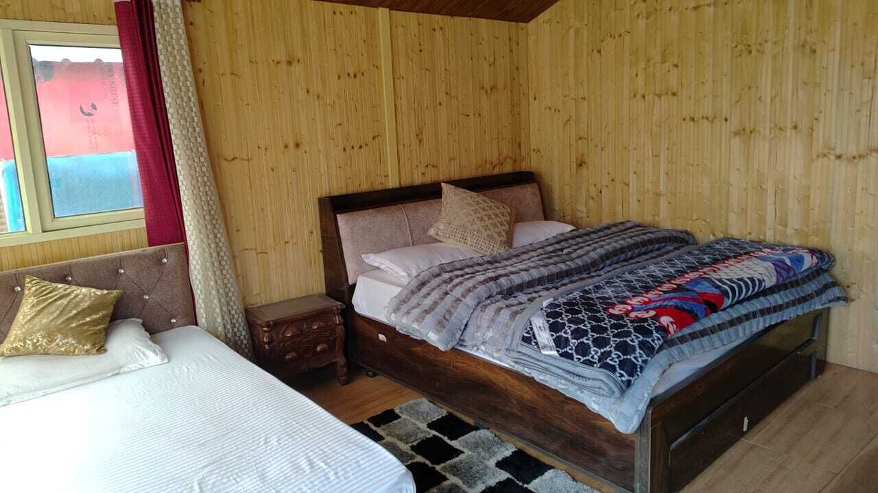 A wooden-paneled room with a bed, a nightstand, and a window with curtains.