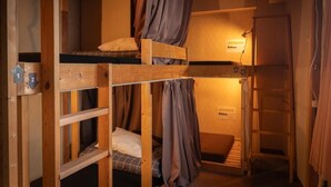 Ein Schlafsaalzimmer mit Etagenbetten, einer Hockerleiter und einer Wandleuchte.