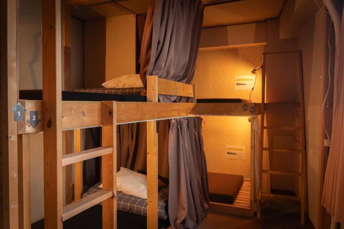 Un dormitorio con literas, una escalera y una lámpara fijada a la pared.