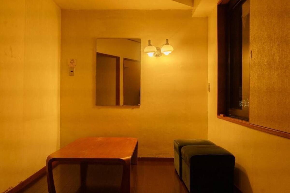 Un pasillo estrecho con un banco de madera, una pequeña mesa y una lámpara fijada a la pared.