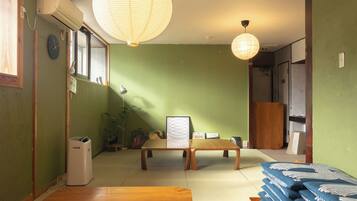 A traditional Japanese room with tatami flooring, a low wooden table, a hanging paper lantern, and a wall-mounted air conditioner.