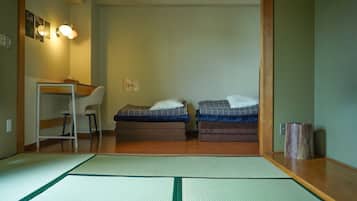 Una habitación con suelo de tatami, dos camas, un escritorio y una silla.