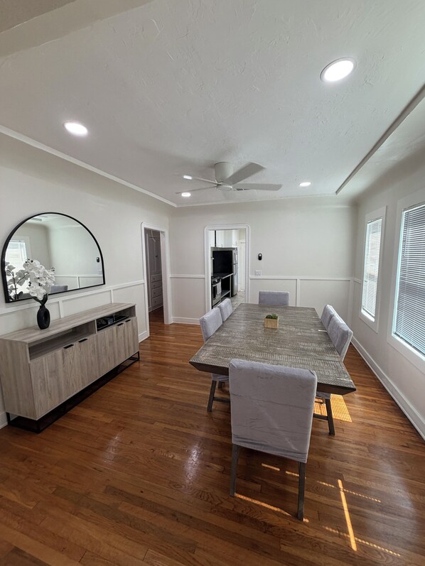 A spacious dining area with a long table, chairs, and a ceiling fan.