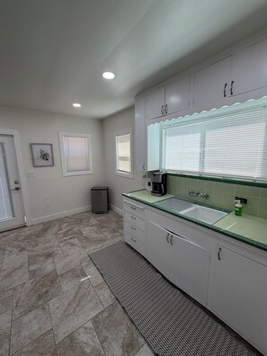 A kitchen with white cabinets, a sink, and a coffee maker.
