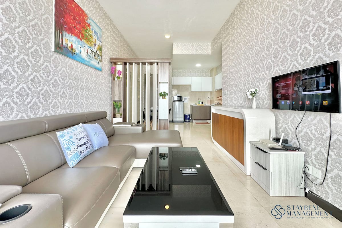 Una sala de estar moderna con un sofá, una mesa de centro y un televisor montado en la pared.