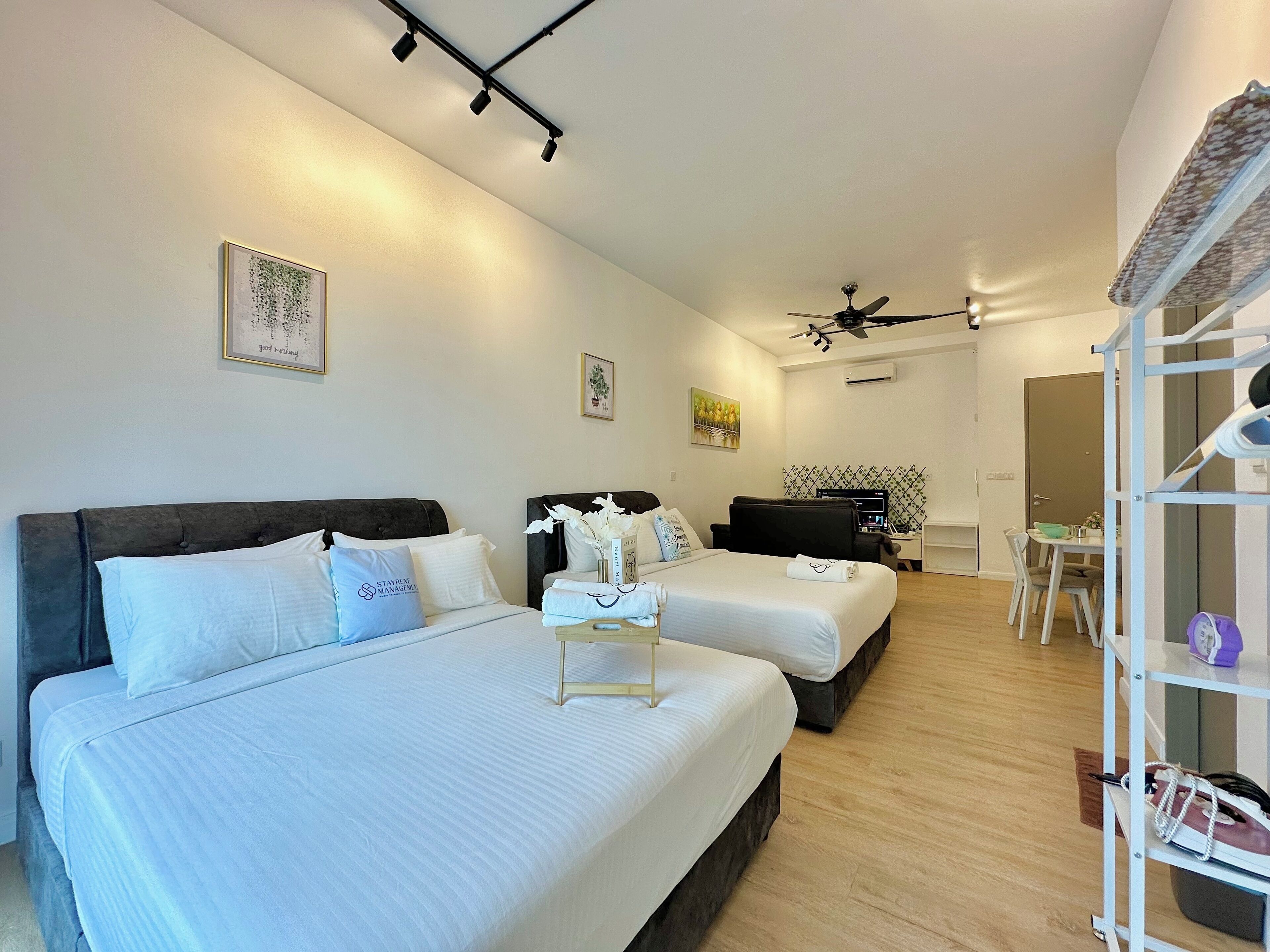 A modern hotel room with two beds, a desk, and a dining area.