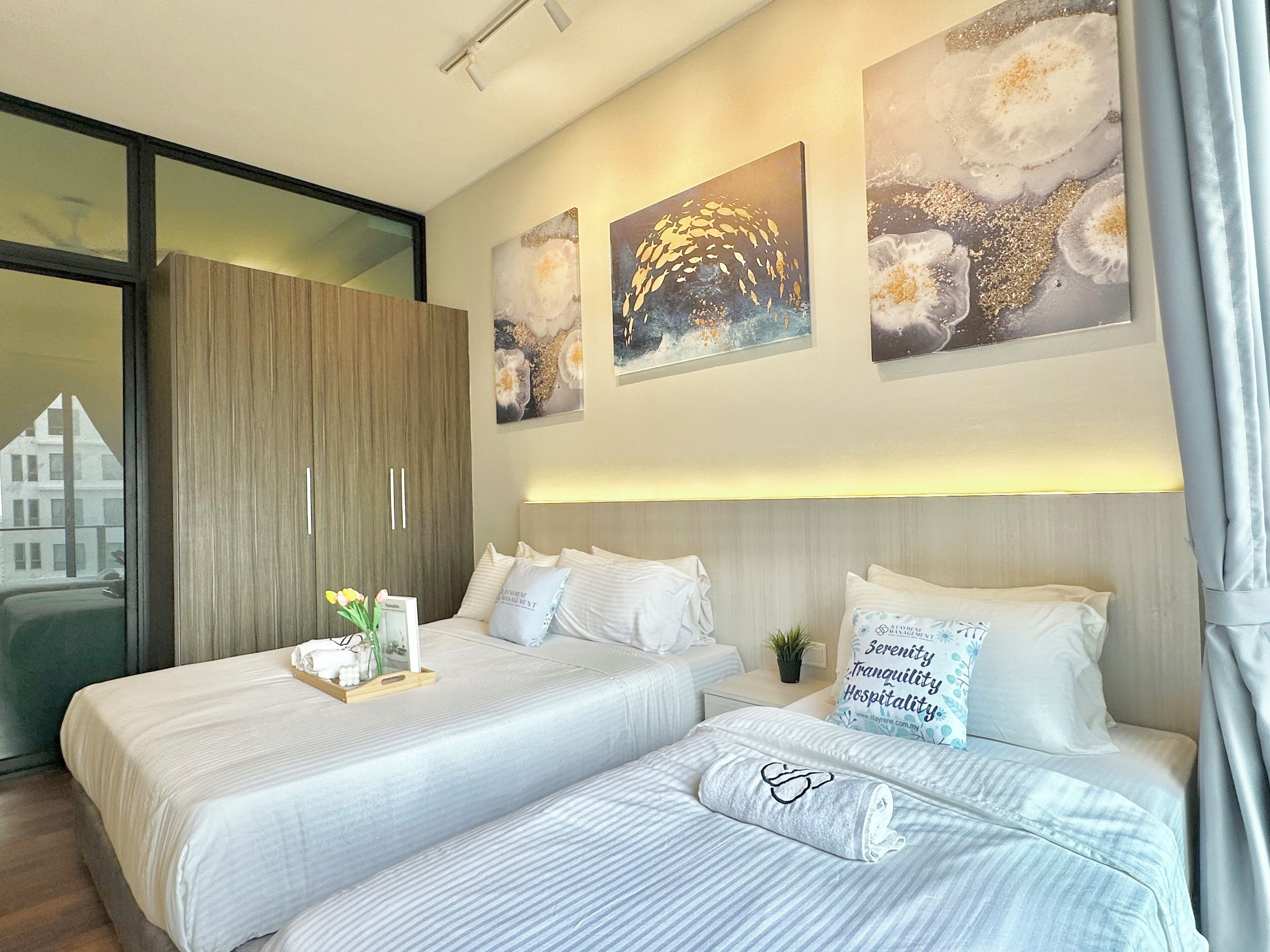 Une chambre d’hôtel avec deux lits, une grande armoire et trois œuvres d’art accrochées au mur.