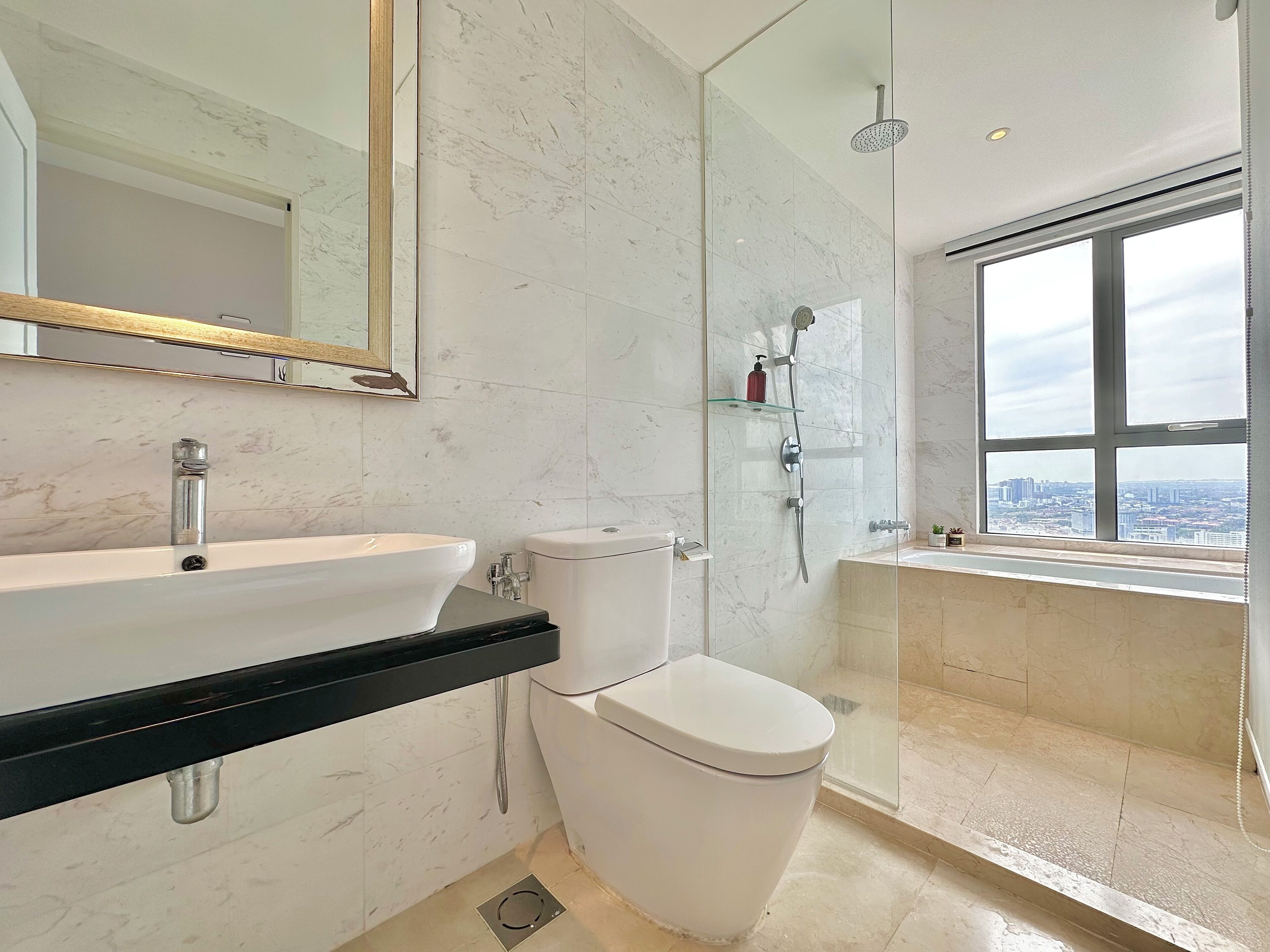 Une salle de bain moderne avec un lavabo blanc, des toilettes et une douche à parois de verre.