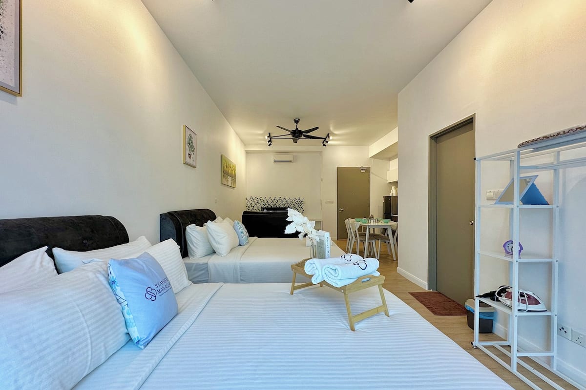 Una habitación de hotel con dos camas, un comedor y un zapatero.