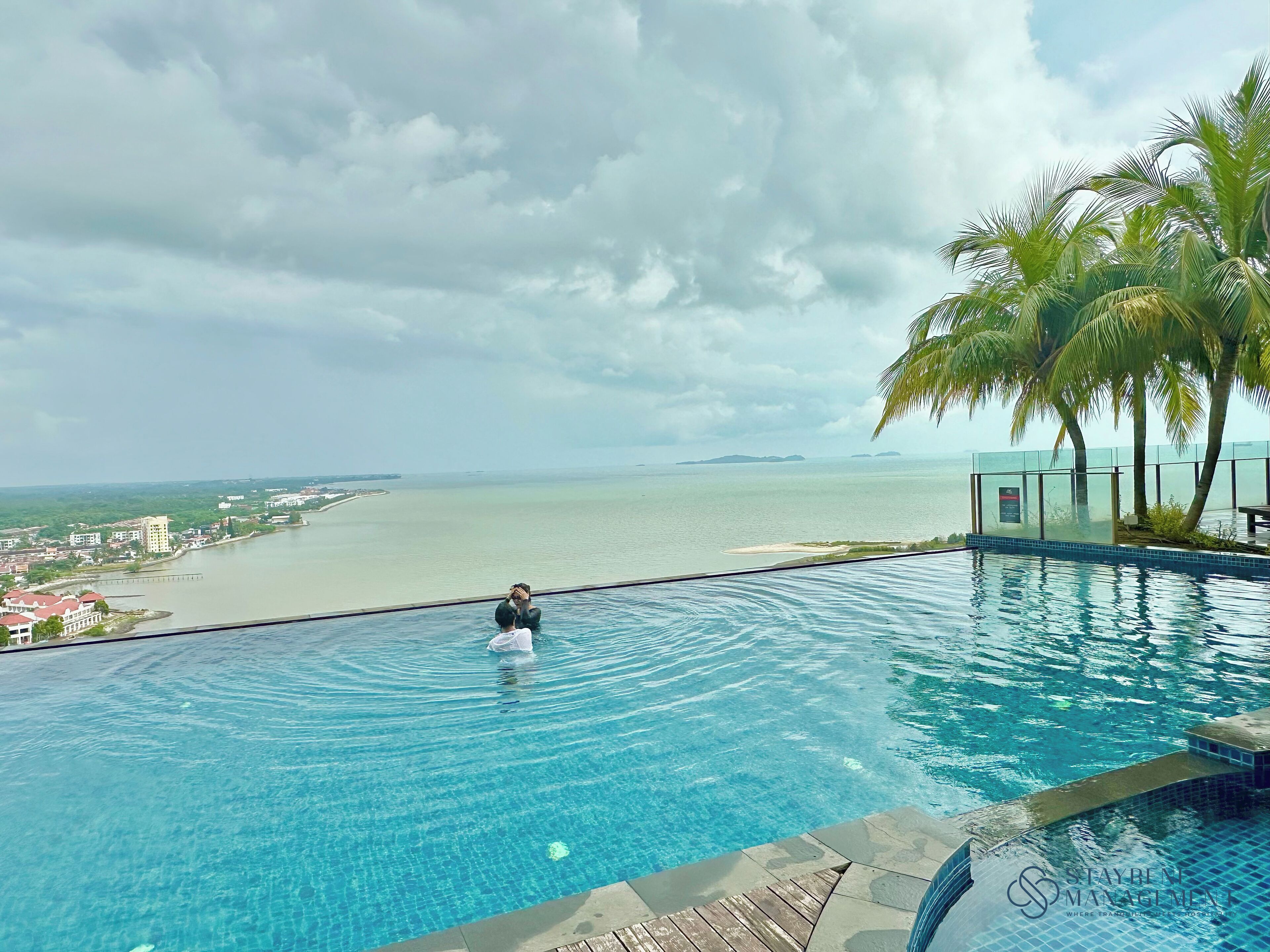 A pool with a view of the sea and a cityscape.