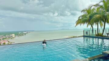 A pool with a view of the sea and a cityscape.