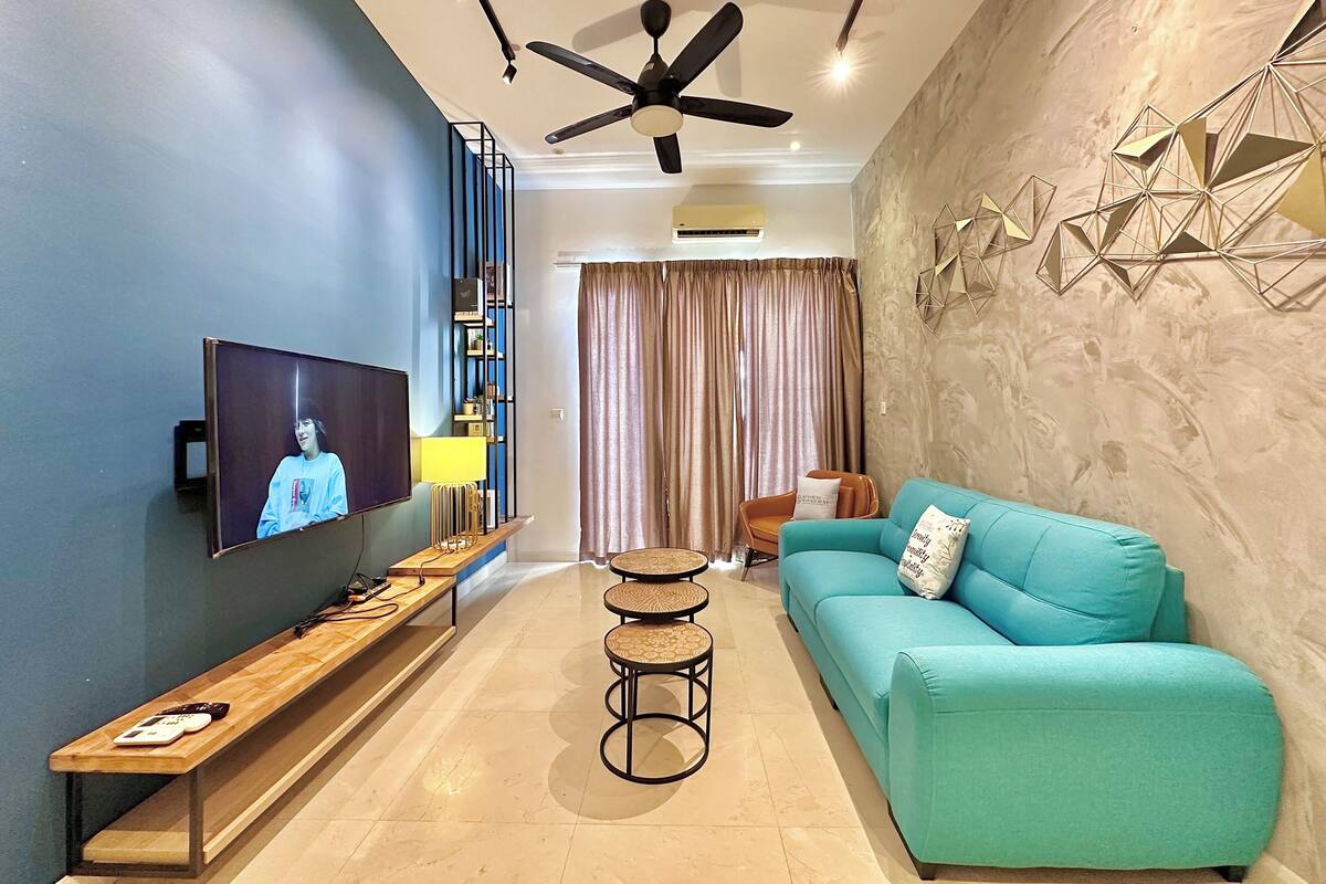Una sala de estar moderna con un sofá color turquesa, un banco de madera, un televisor y un ventilador de techo.