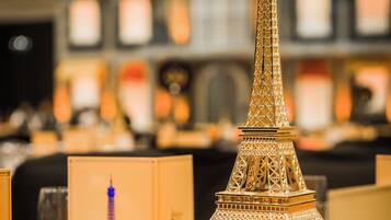 A table with a decorative Eiffel Tower centerpiece, surrounded by pink flowers and clear glassware.