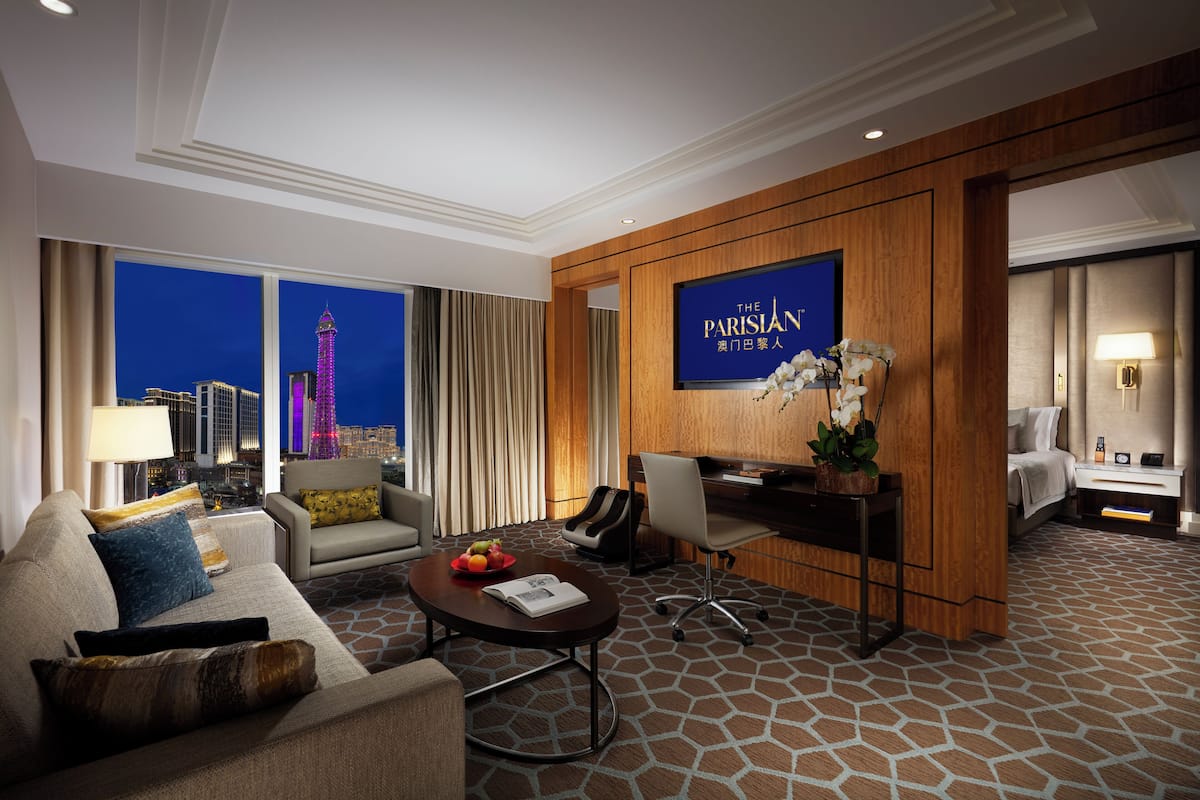 A hotel room with a cityscape view, a television, a desk, a sofa, and a coffee table.
