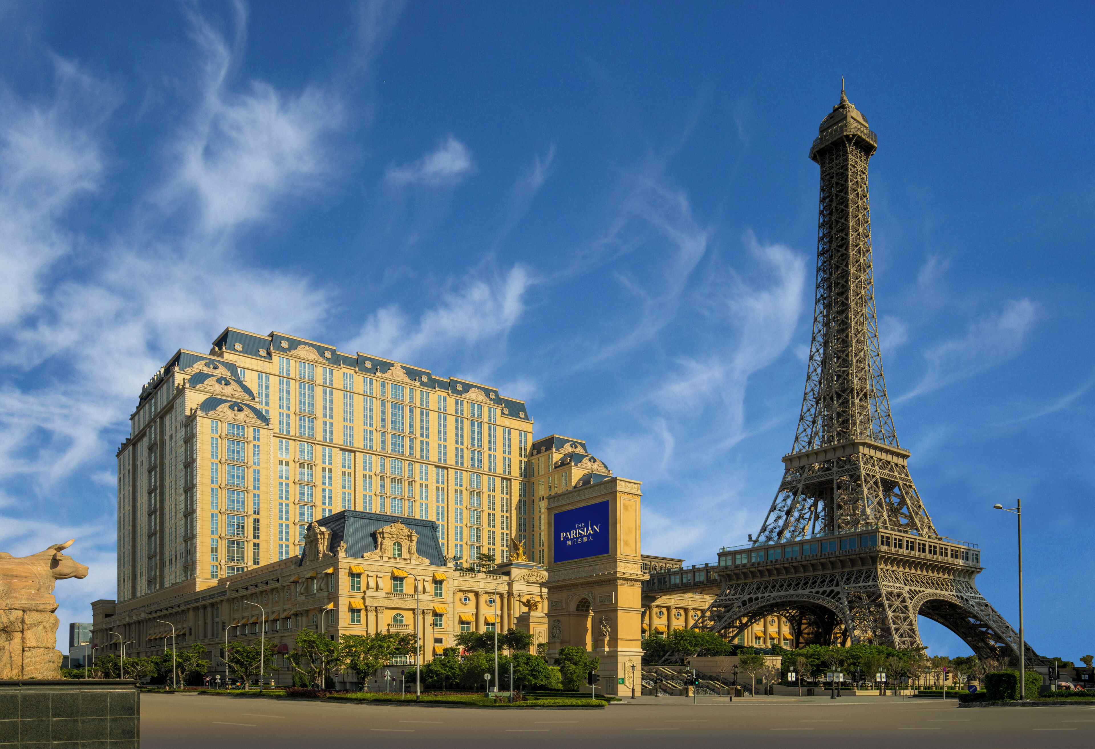 A large hotel with a prominent tower and the Eiffel Tower in the background.