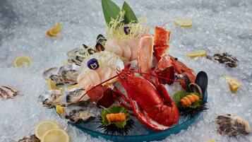 A seafood platter with lobster, mussels, oysters, and lemon slices on ice.