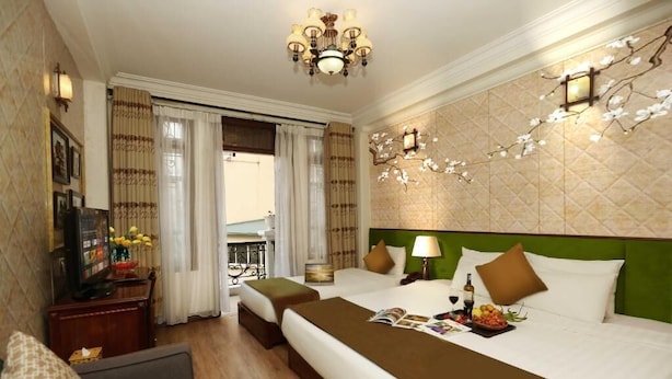 A hotel room with a large bed, a television, a desk with a computer, and a view of the outdoors. - Hanoi Golden Lotus & Spa (Hanoi)