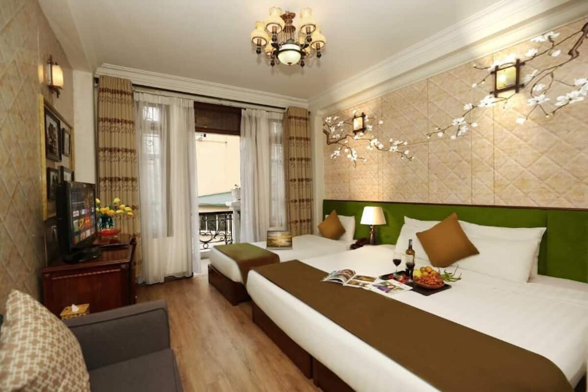 A hotel room with a large bed, a television, a desk with a computer, and a view of the outdoors.