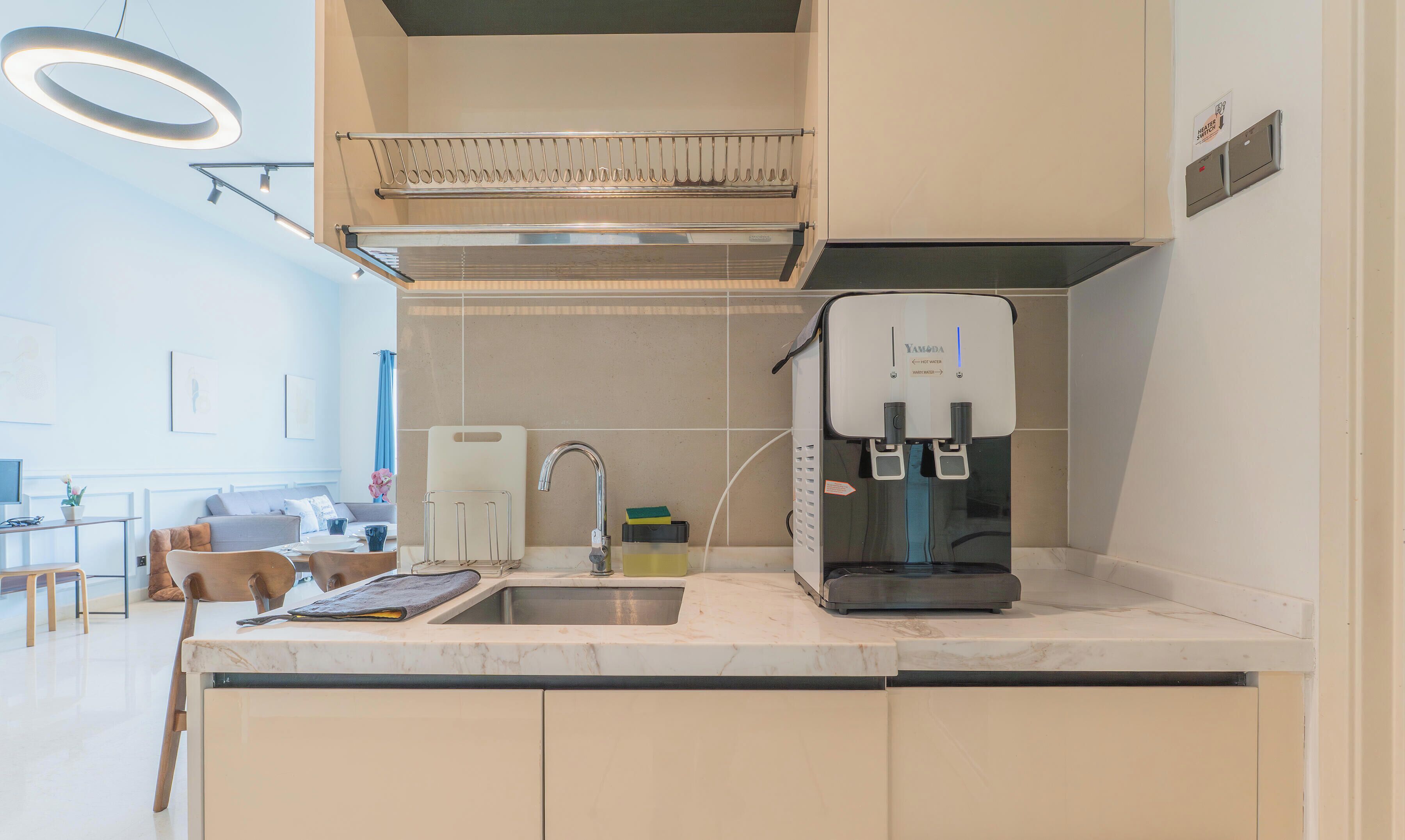 A modern kitchen with a built-in water dispenser, a stainless steel range hood, and a dining area with a table and chairs.