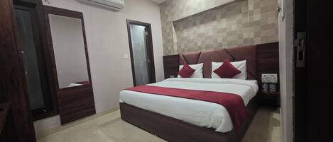 Habitación de hotel con cama, espejo, armario y aire acondicionado instalado en la pared.
