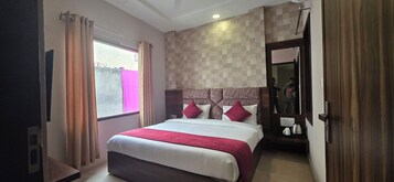 Una habitación de hotel con una cama grande, una ventana con cortinas, una pared a cuadros y un espejo.