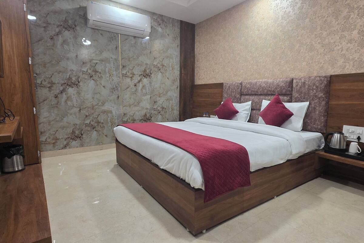 Un dormitorio moderno con una cama de madera, una pared de mármol y una televisión empotrada.
