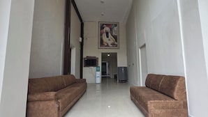 A hallway with two brown sofas on either side, a water dispenser, and a television on the wall. - Golden Pearl Infront Golden Temple Gate (Amritsar)