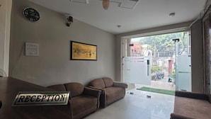 A reception area with a sofa, a clock, a framed picture, and a sign indicating the reception. - Golden Pearl Infront Golden Temple Gate (Amritsar)