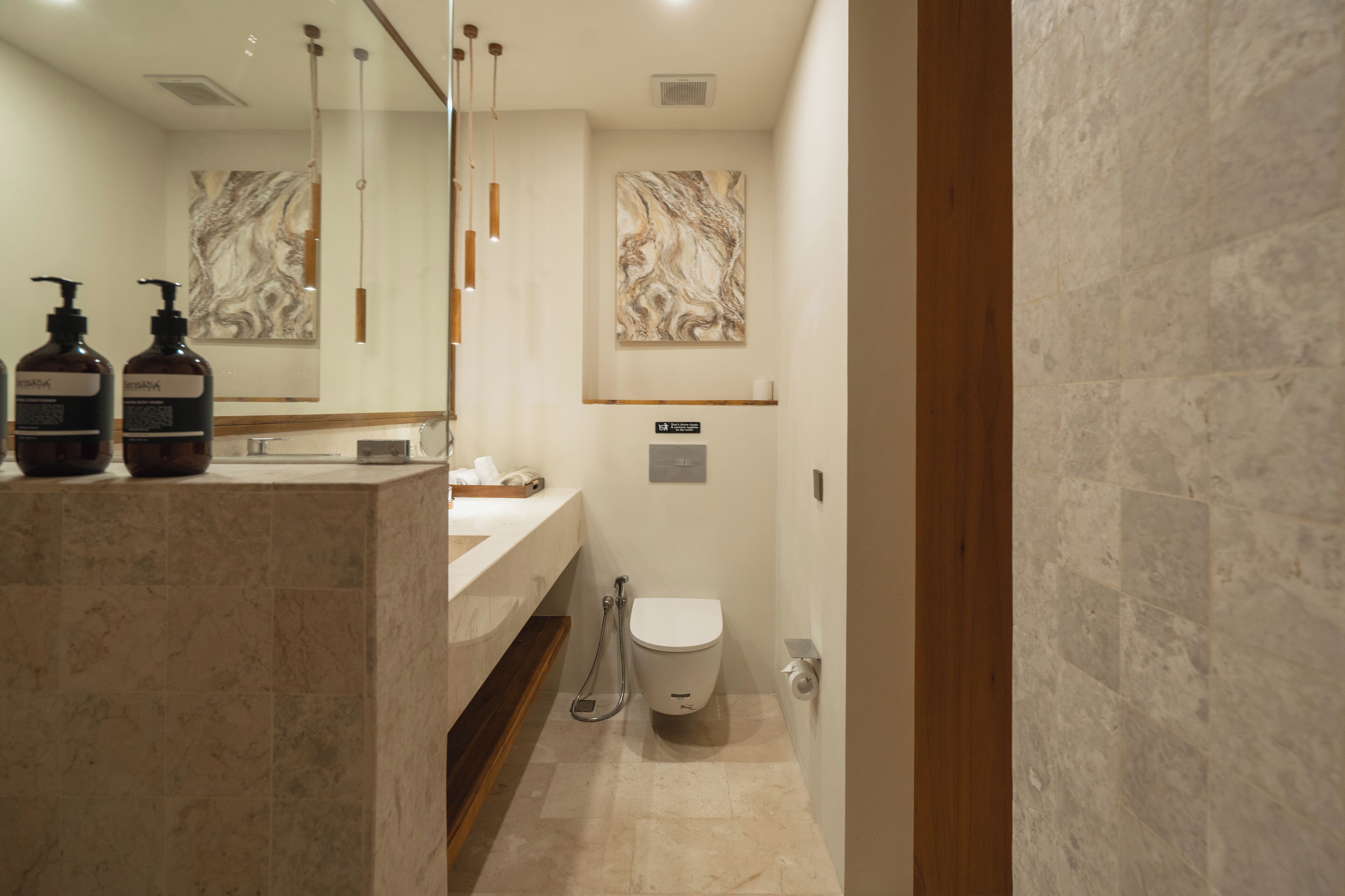 A modern bathroom with a marble sink, two hand soap dispensers, a toilet, and a shower.