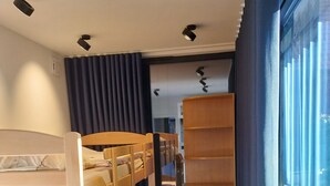 Habitación con literas, un escritorio de madera, una ventana con cortinas e iluminación empotrada en el techo.