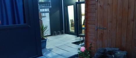 A modern outdoor area with a stone water feature, a wooden door, and a potted plant.