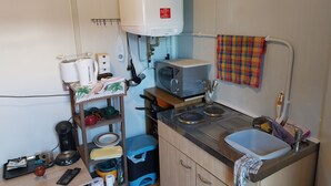 Cocina compacta con microondas, hervidor y un lavamanos pequeño.