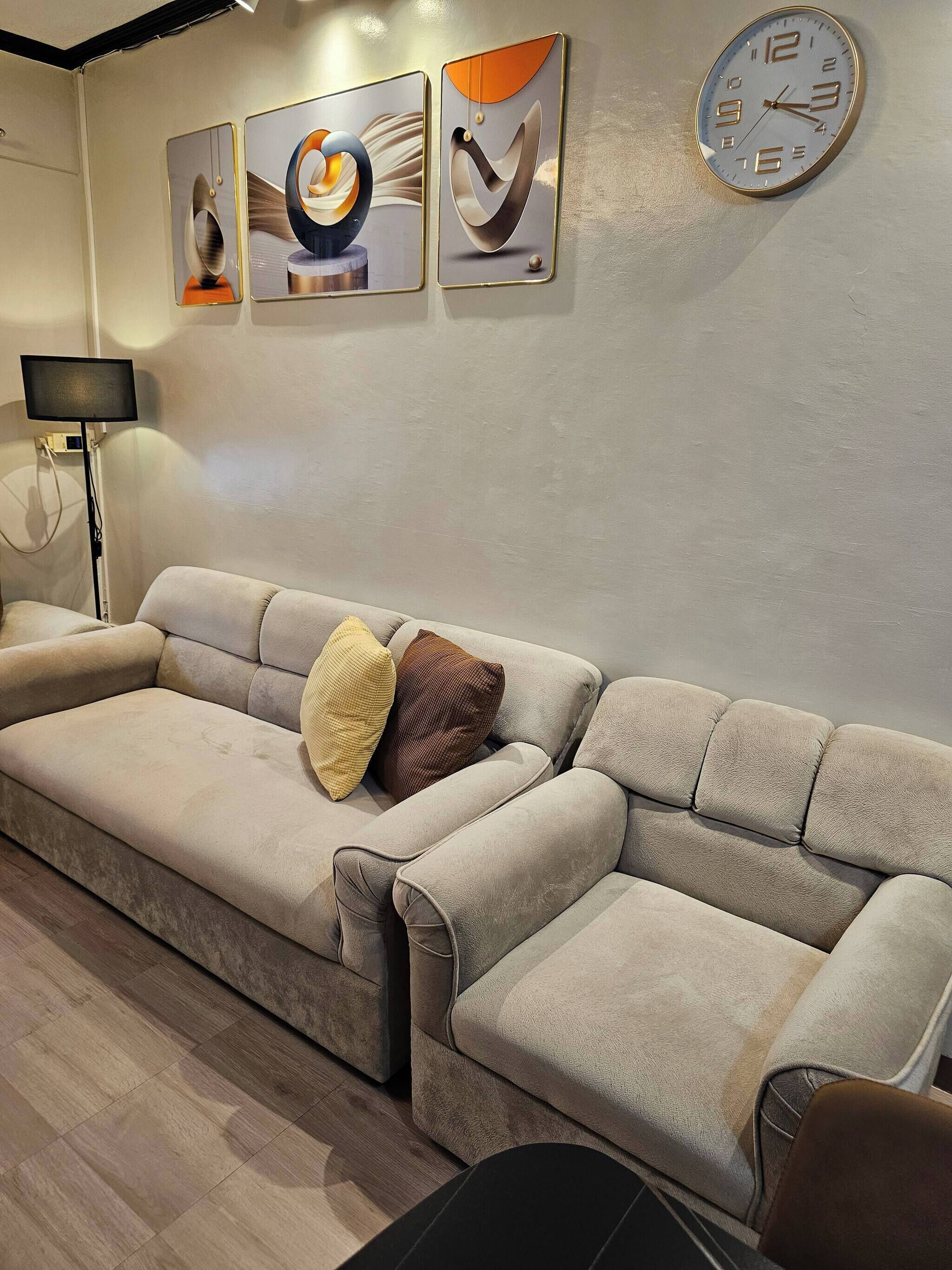 A modern living room with a sectional sofa, a flat-screen TV, and abstract wall art.