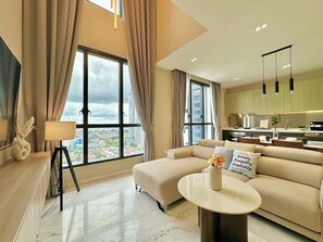Una sala de estar moderna con un sofá, una mesita de centro y vistas a la ciudad a través de grandes ventanales.