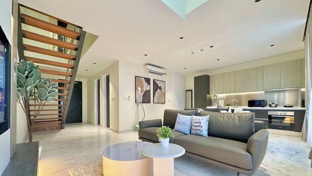 A modern living room with a sofa, coffee table, and a staircase. - Setia Sky 88 Johor Bahru by Stayrene (Johor Bahru)